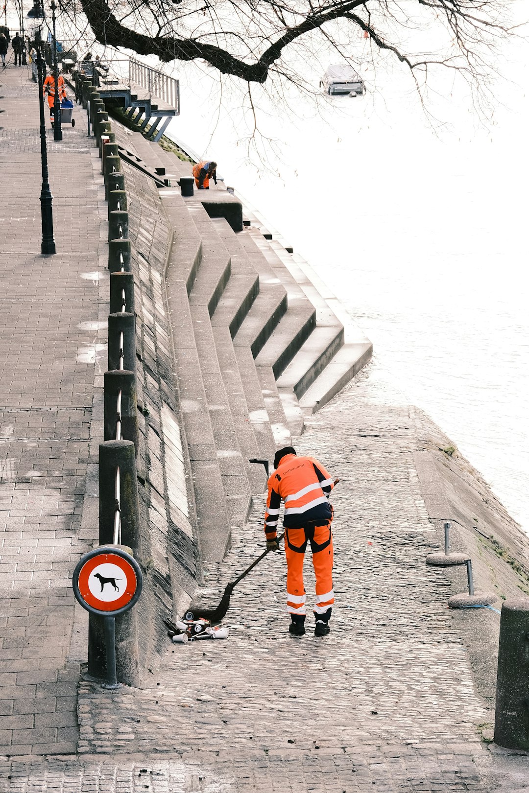 a-man-in-an-orange-safety-suit-is-cleaning-a-street-cssd6bqgbam